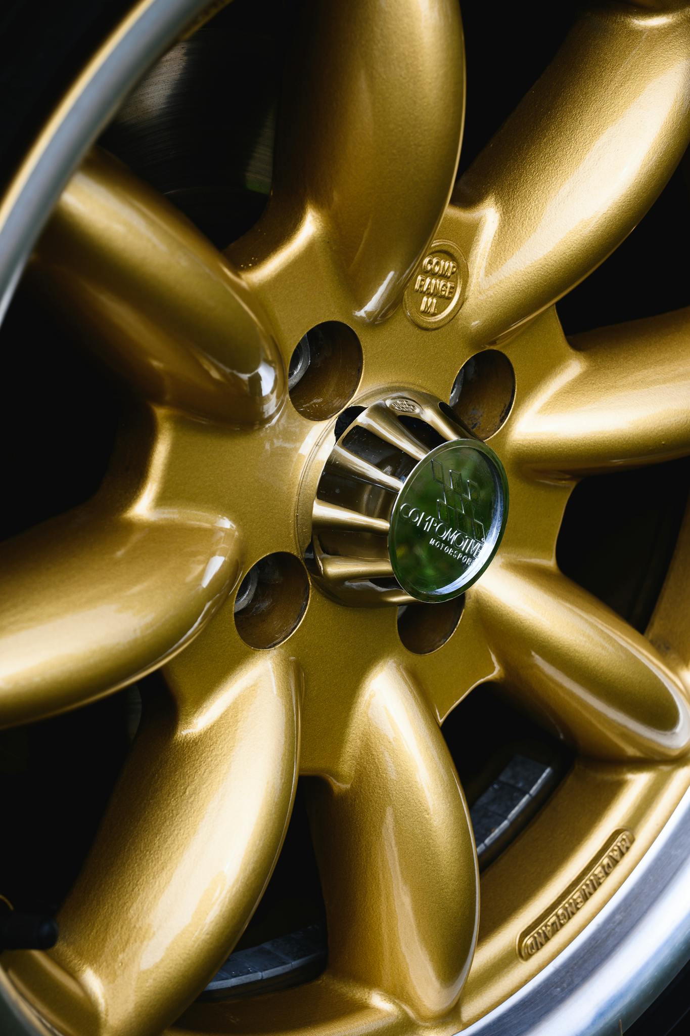 Close-up shot of a golden car wheel with chrome accents, highlighting its luxury and classic design.